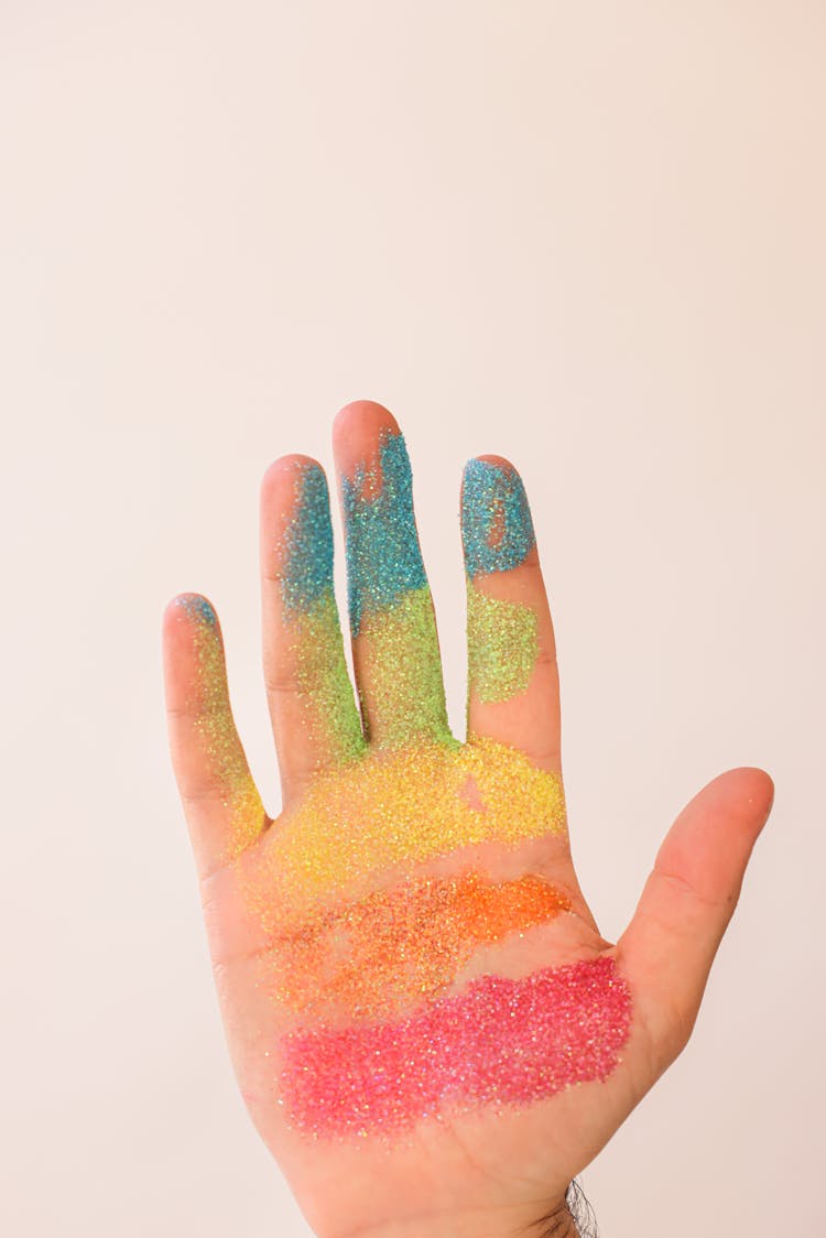 A Hand Covered In Rainbow Glitters