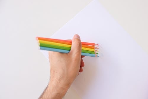 Person Holding Green and Red Coloring Pencils