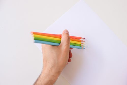 Free Close-up of hand using rainbow colored pencils on paper, showing creativity. Stock Photo