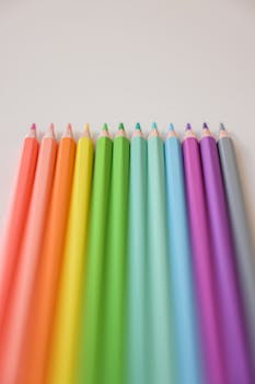 A stunning display of colored pencils aligned in a rainbow spectrum on a white surface.