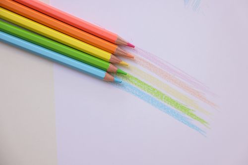 Free Close-up of vibrant colored pencils arranged on a white surface, showing artistic sketches. Stock Photo
