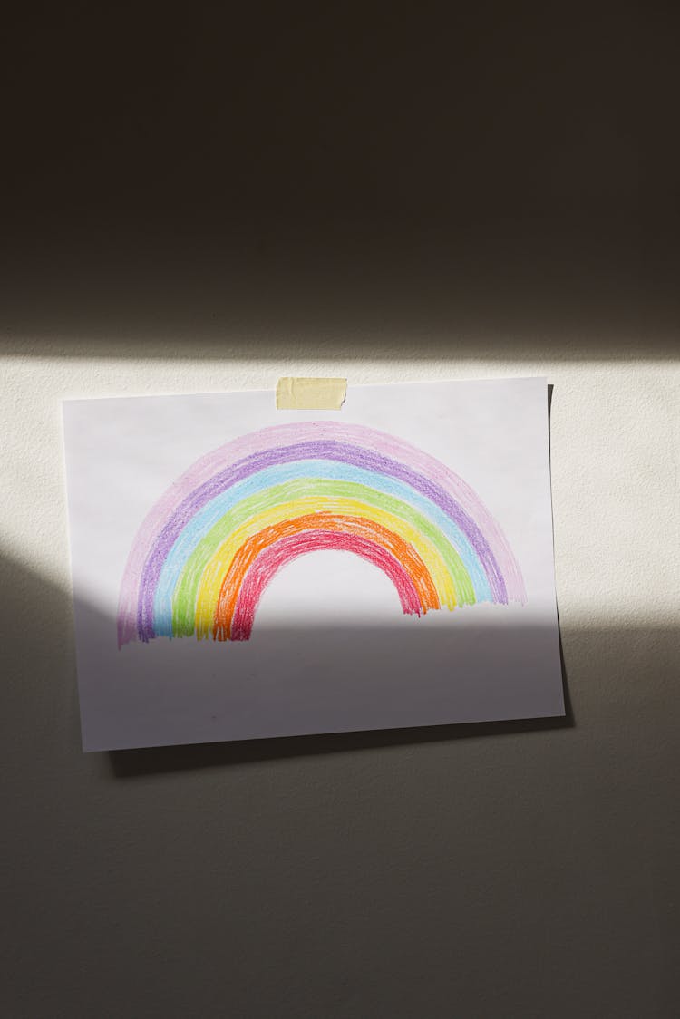 An Artwork With Rainbow Drawing Posted On A Wall