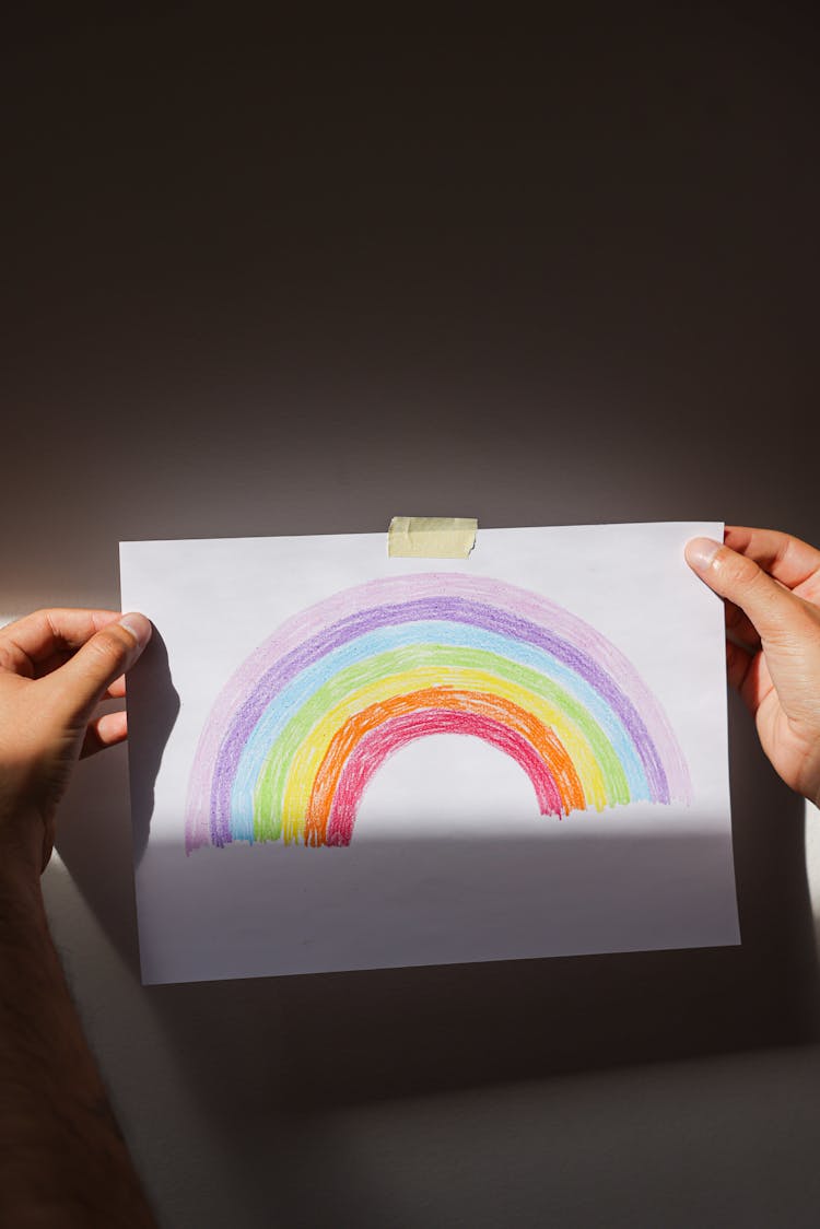 Hands Holding A Bond Paper With Rainbow Drawing