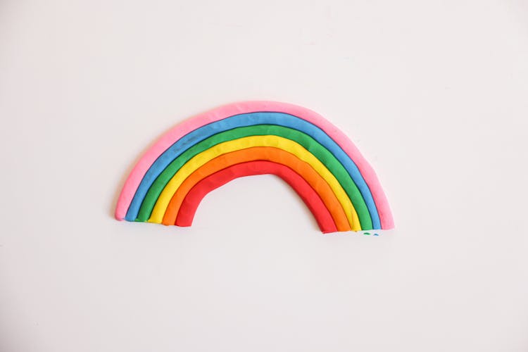 A Rainbow Art Made With Clay On A White Surface