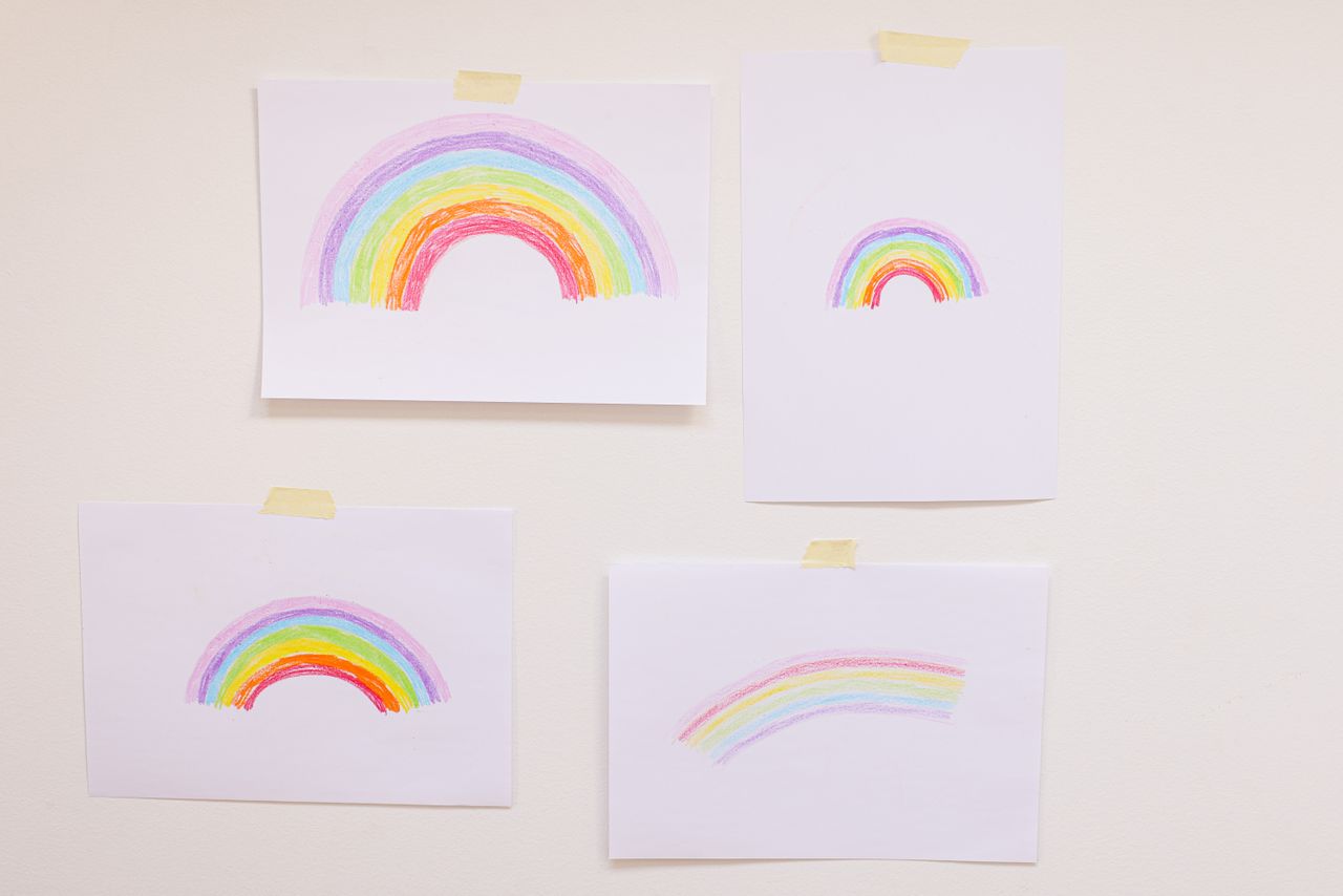 four hand drawn rainbow illustrations taped on a wall creating a vibra