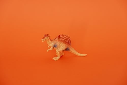 Free Dinosaur Toy Standing on Orange Background Stock Photo