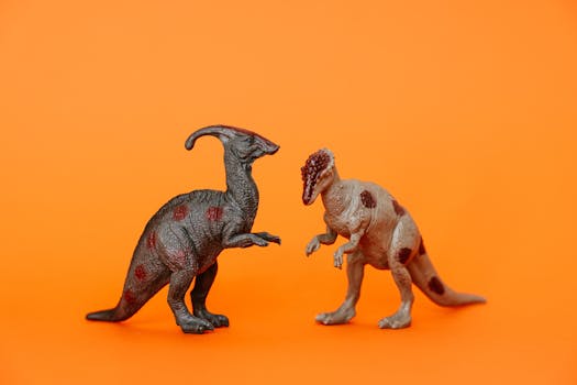 Two dinosaur figurines on an orange background, showcasing prehistoric toy collectibles.