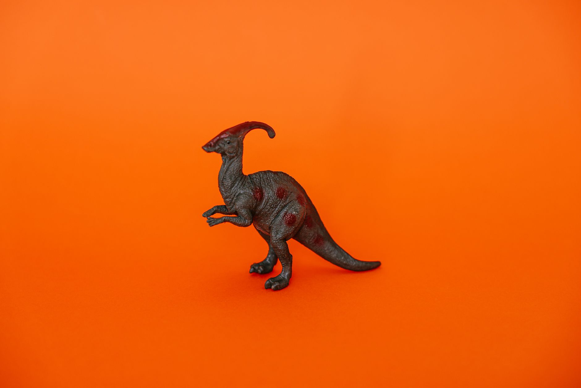 Miniature dinosaur figurine on a bright orange backdrop, perfect for creative projects.