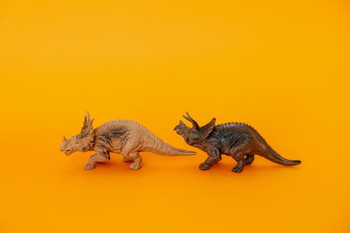 A Brown and Cream Toy Dinosaurs on Yellow Surface