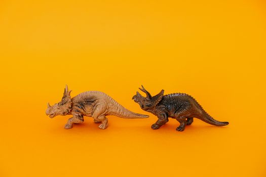 Triceratops and dinosaur toy models displayed against a bold yellow backdrop, creating a prehistoric theme.