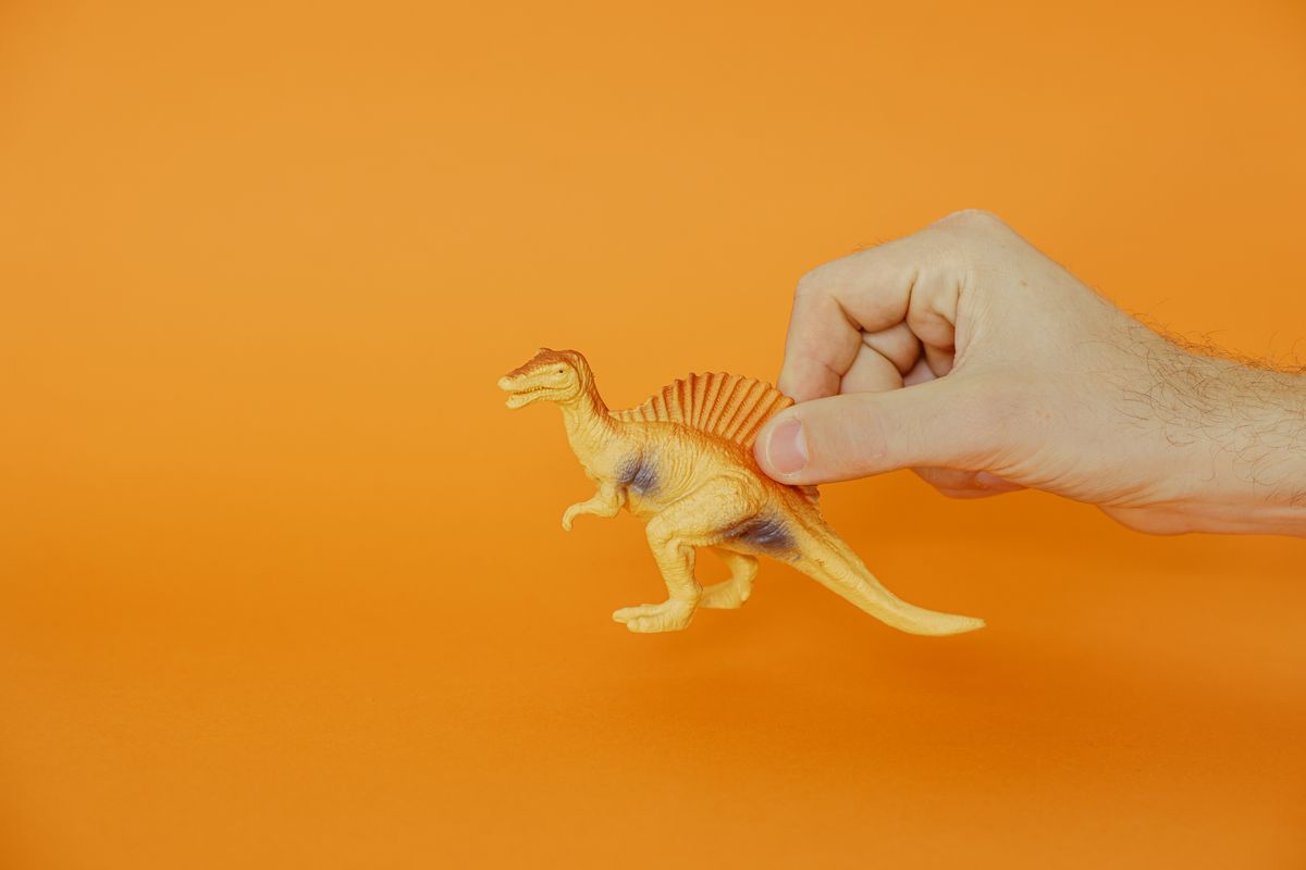 Hand holding a dinosaur toy for dinosaur crafts for kids fossils