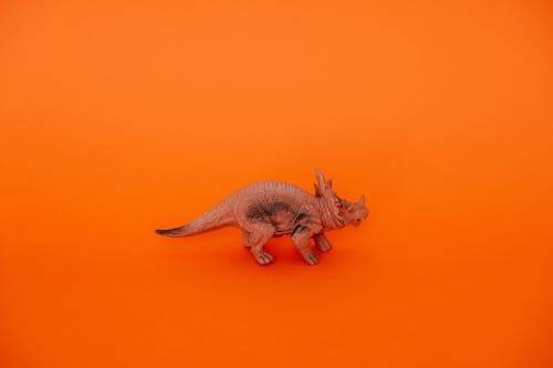 Studio Shoot of a Plastic Dinosaur Figurine on Orange Background