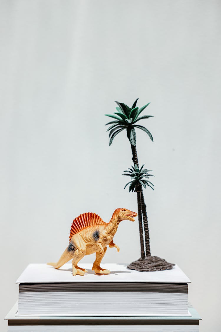 Studio Shot Of A Plastic Dinosaur And Palm Tree On A Book