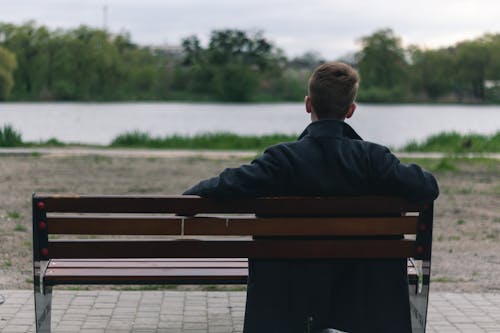 A Person in Black Coat Sitting on a Bench