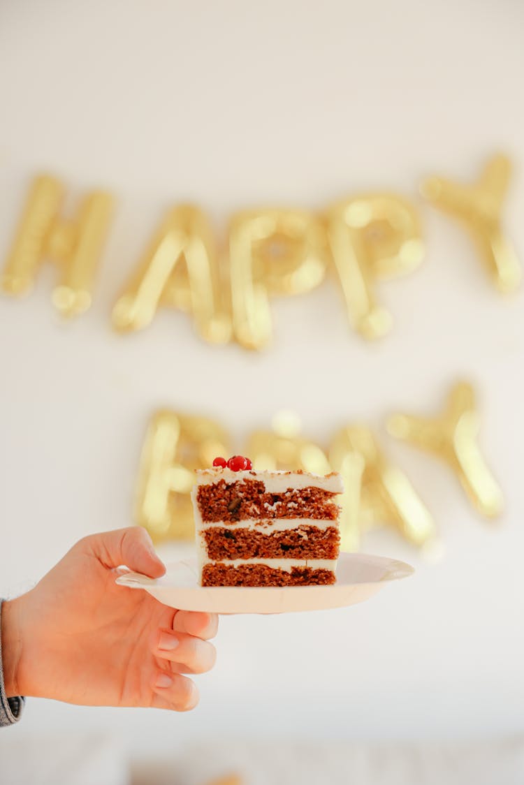 A Person Holding A Plate With Cake 