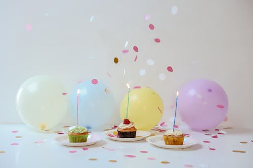 A Cupcakes on the Table with Lighted Candles and Balloons