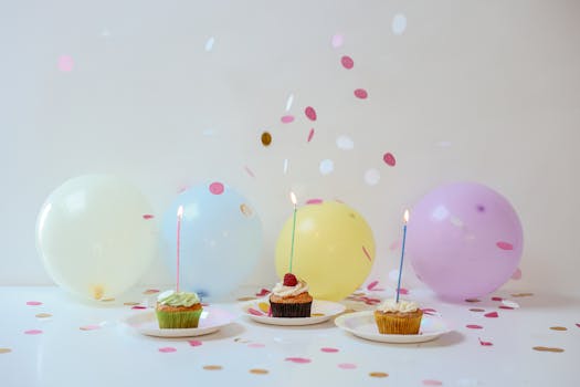 Vibrant birthday setup with cupcakes, balloons, and confetti on a table.
