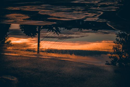 Free A stunning sunset reflection captured in a street puddle post-rain. Stock Photo