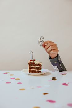 Slice of birthday cake with candles shaped as number 16, surrounded by confetti, celebrating a sweet milestone.