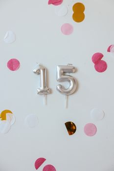 Silver number 15 birthday candles surrounded by vibrant confetti. Perfect for quinceañera or birthday celebration concepts.