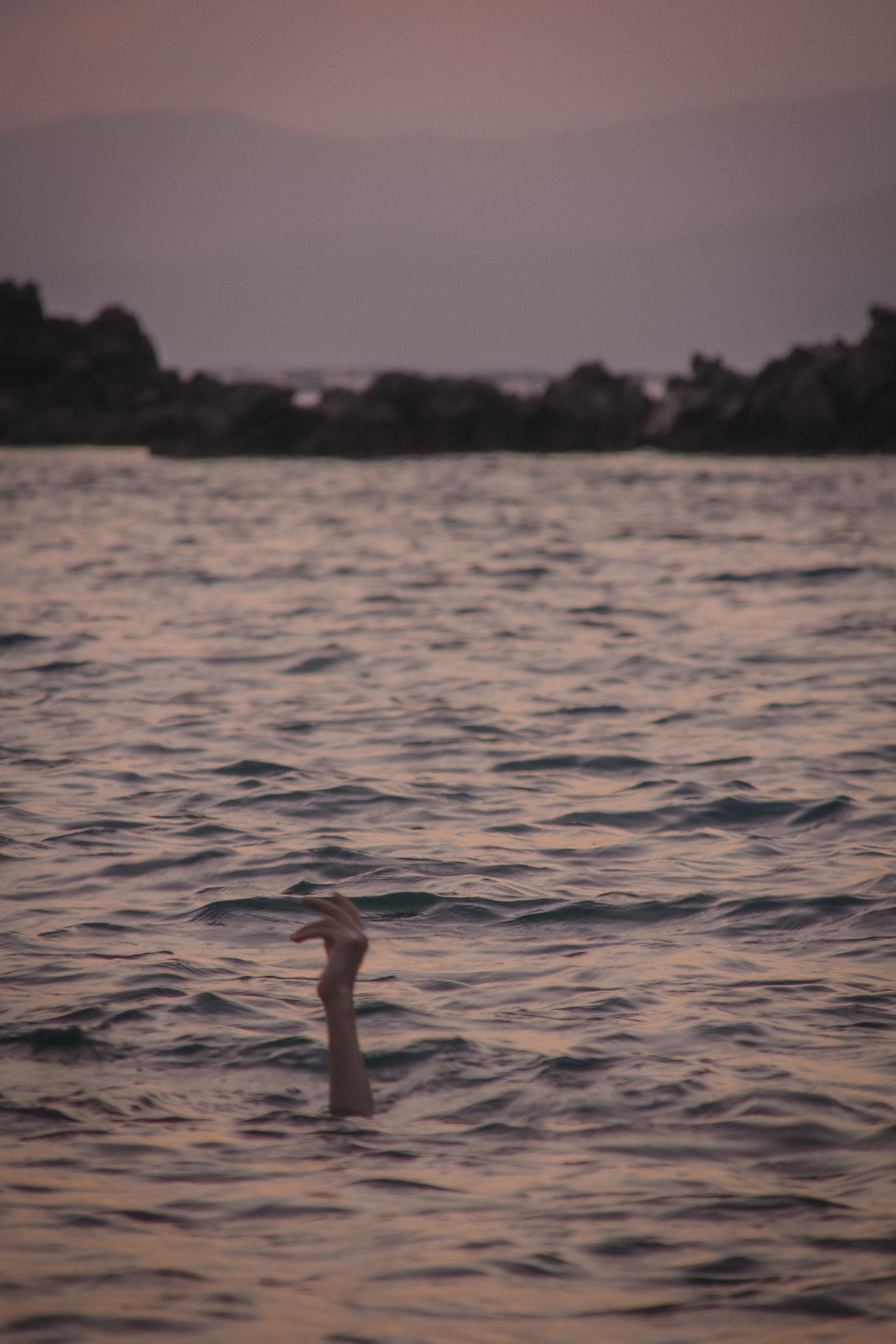 A woman laying in the water at sunset · Free Stock Photo