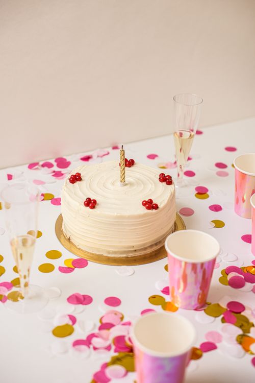 Free Celebratory cake topped with berries surrounded by confetti and champagne glasses. Stock Photo