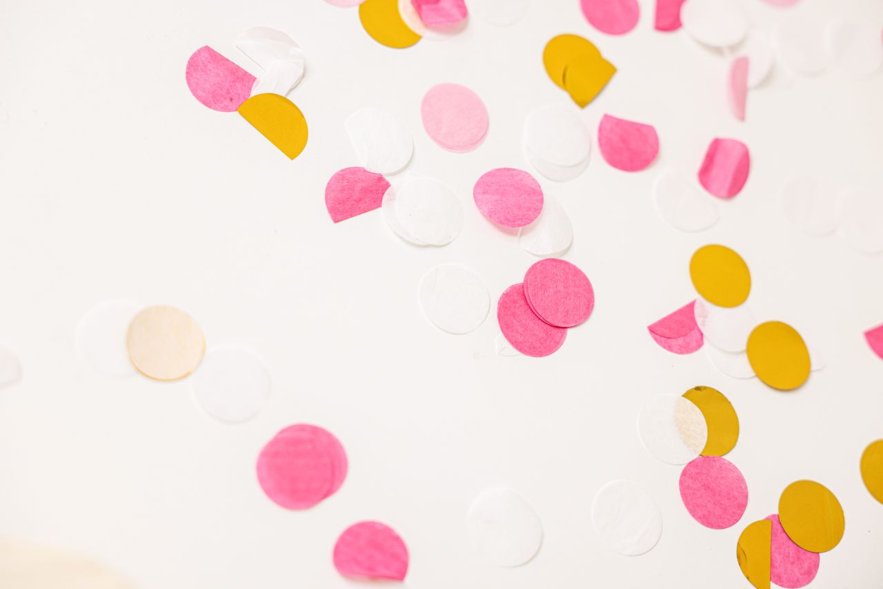 starry-table-confetti Colorful confetti pieces scattered on a white surface