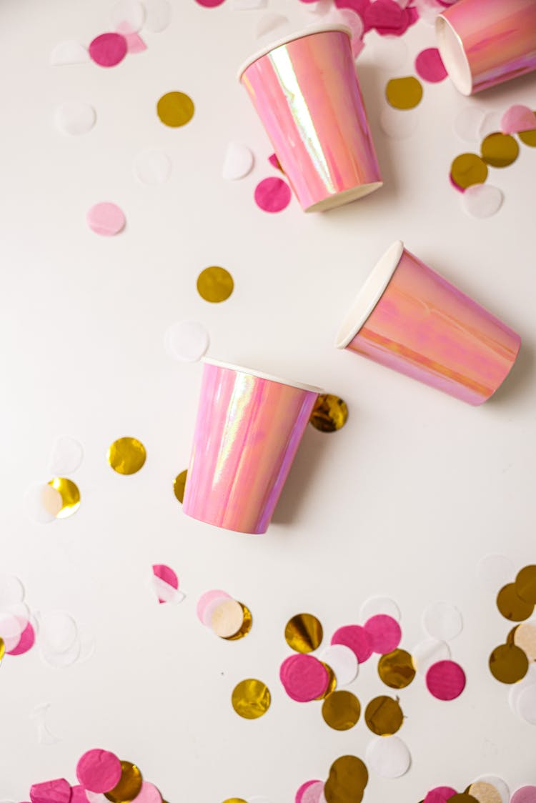 Pink Disposable Cups Lying On A White Surface With Confetti