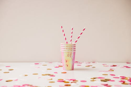 Colorful Paper Cups with Paper Straws Standing on a Table with Confetti 