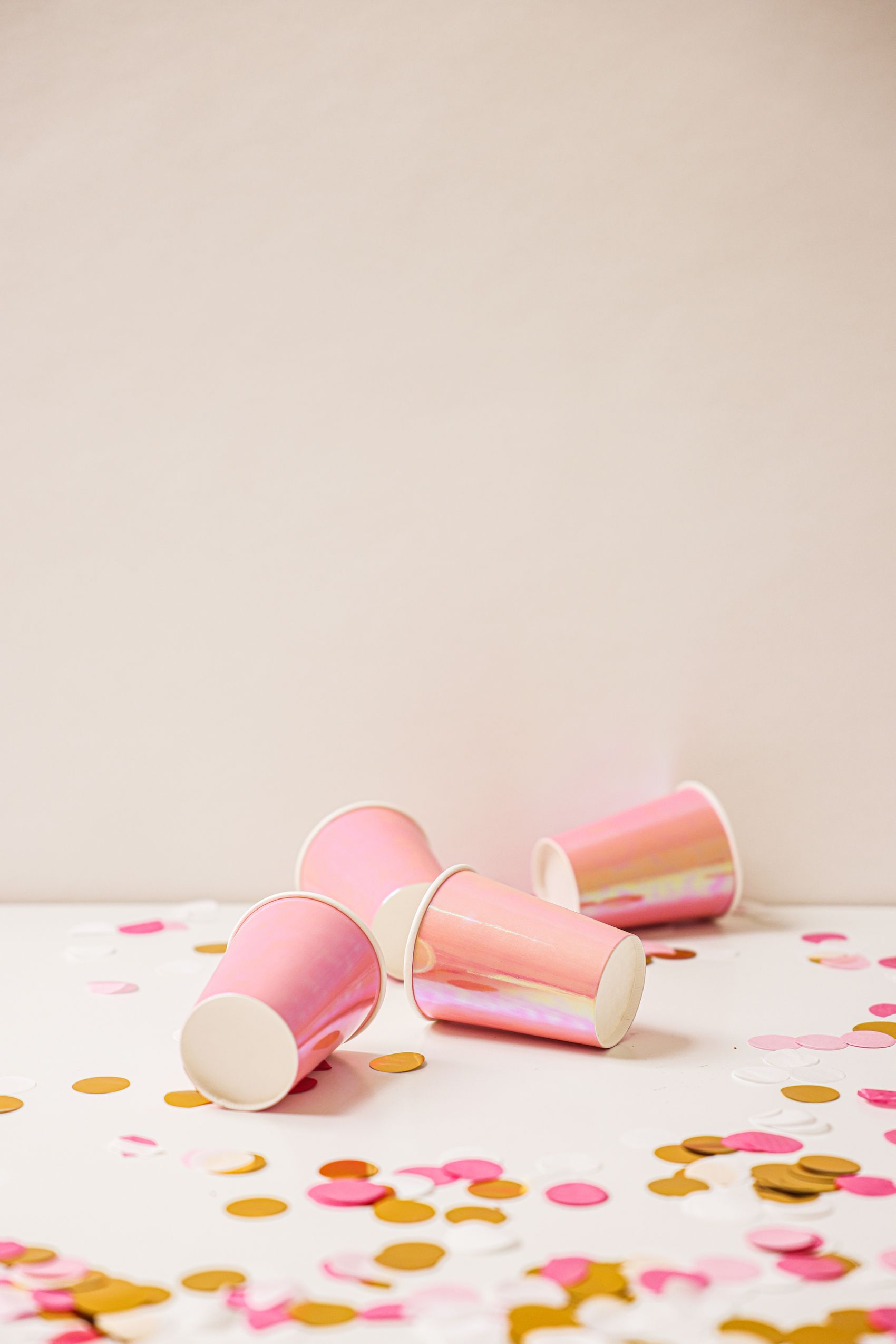 Colorful paper cups and party accessories arranged with festive confetti
