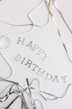 Stylish happy birthday text with silver and gold ribbons on a white background.