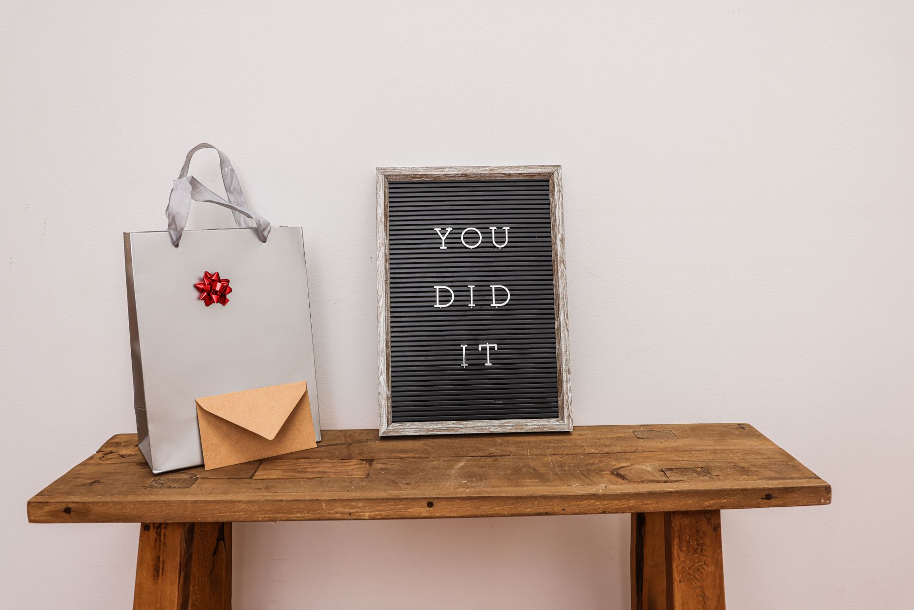 Gift bag with envelope and congratulatory letter board on wooden table.