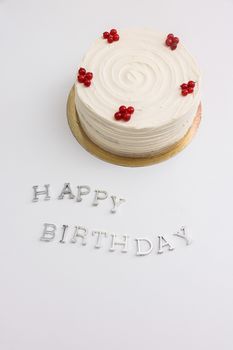 Celebratory white birthday cake with berries on a minimal background with 'Happy Birthday' text.