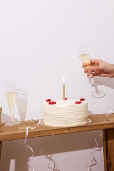 White cake with a candle and champagne glasses, perfect for celebrations.