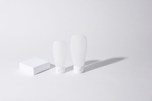 Minimalist mockup of cosmetic containers with empty white packaging, ideal for branding.