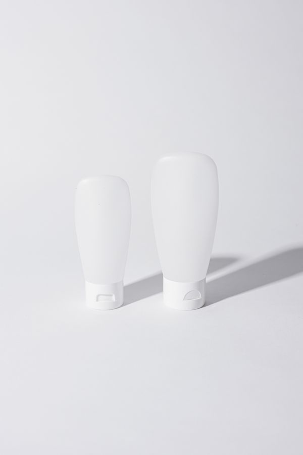 Two unlabelled white cosmetic tubes on a pale studio backdrop — photo by Cup of Couple on Pexels