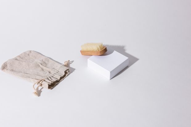 Soft shoe brush and dust bag arranged on a pale surface — photo by Cup of Couple on Pexels