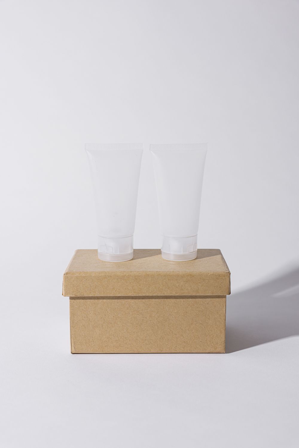 Clear cosmetic tubes standing on a kraft box