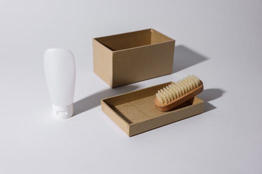 A clean, minimalist mockup featuring a cardboard box, a brush, and a white bottle, ideal for product packaging concepts.