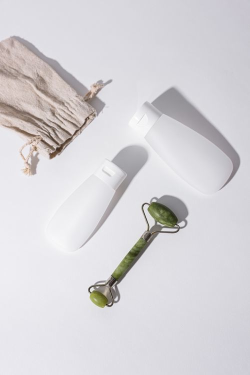 Free Flat lay of skincare bottles and jade face roller on a white background. Ideal for beauty concepts. Stock Photo