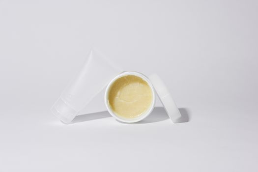 Studio shot of white plastic containers with yellow cream product on a white background.