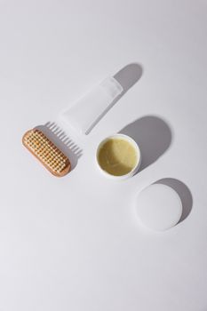 Top view of skincare products including a brush and cream on a white background with copyspace.