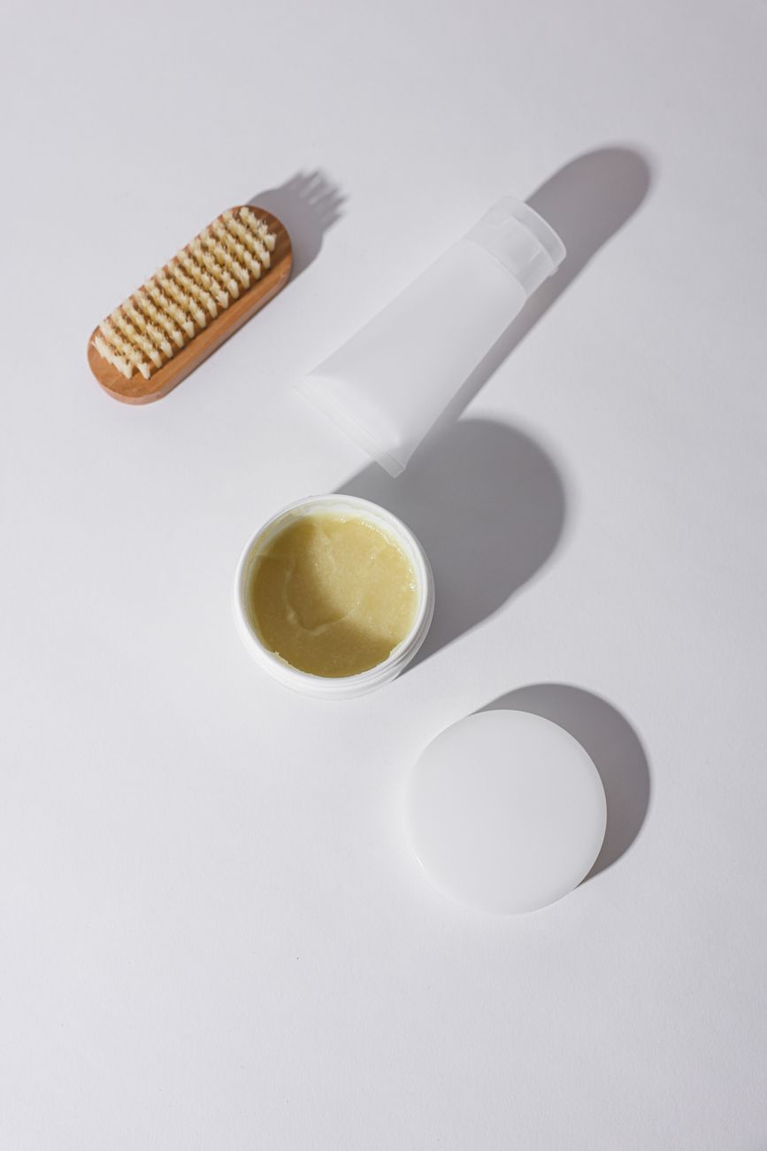 Top view of skincare cream and grooming brush on white background.