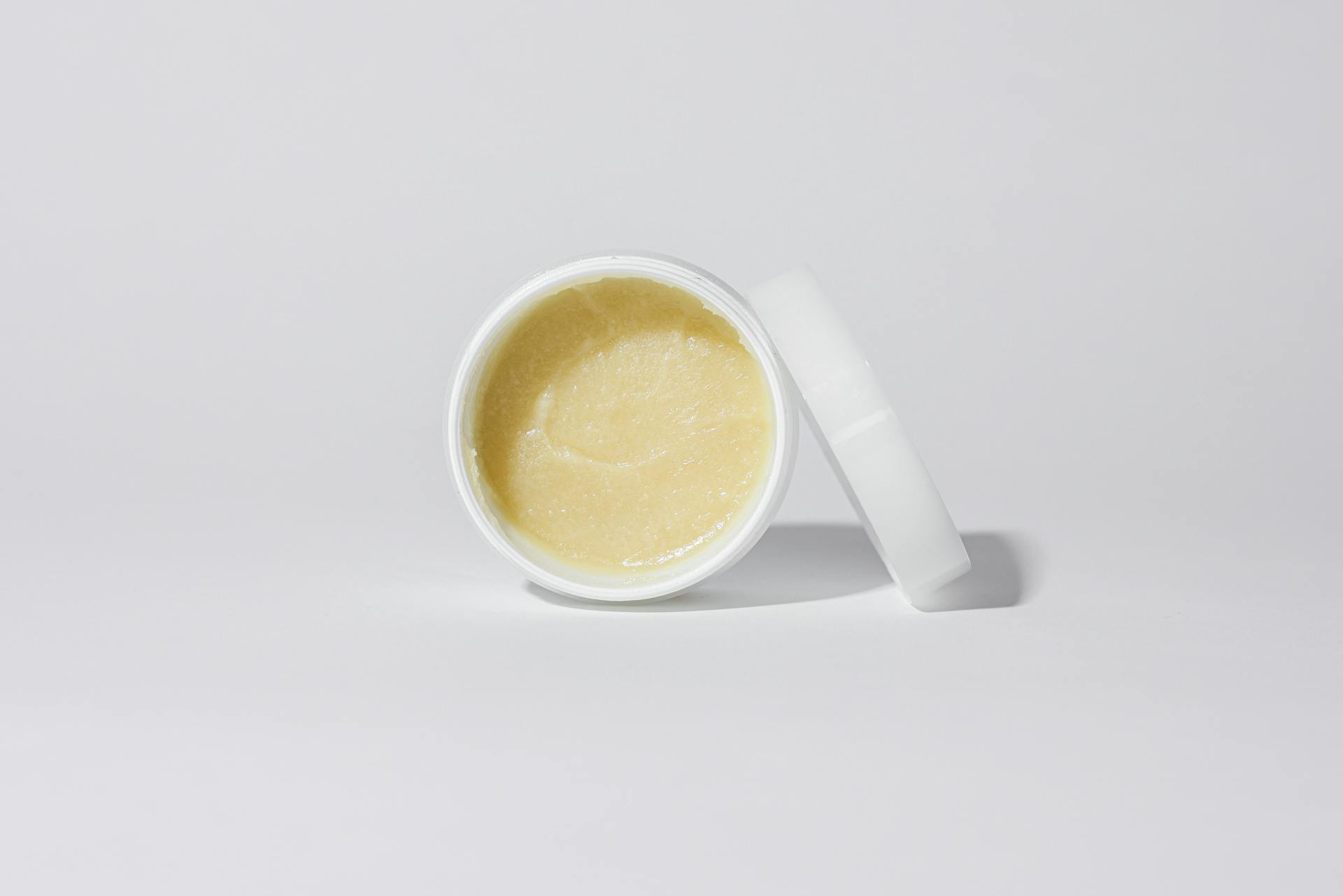 Clean and simple close-up of a cosmetic cream in a white container against a neutral background.