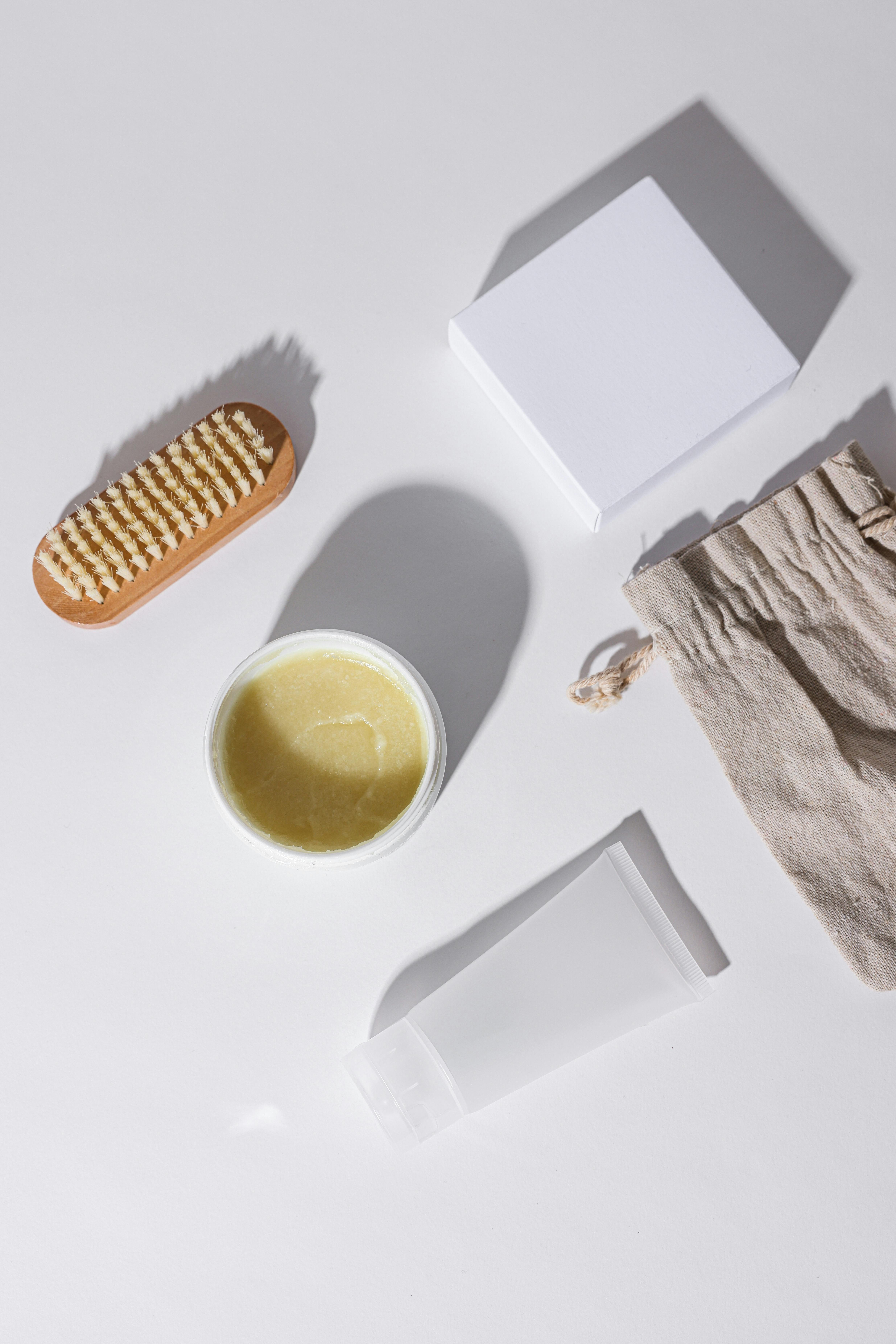 a wooden brush beside assorted containers on a white surface