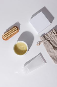 Flat lay of skincare products including a brush, container, and pouch on a white surface.