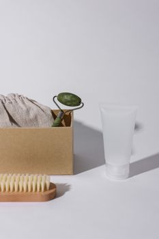 A minimalist composition of skincare products on a white surface, featuring a jade roller and brush.
