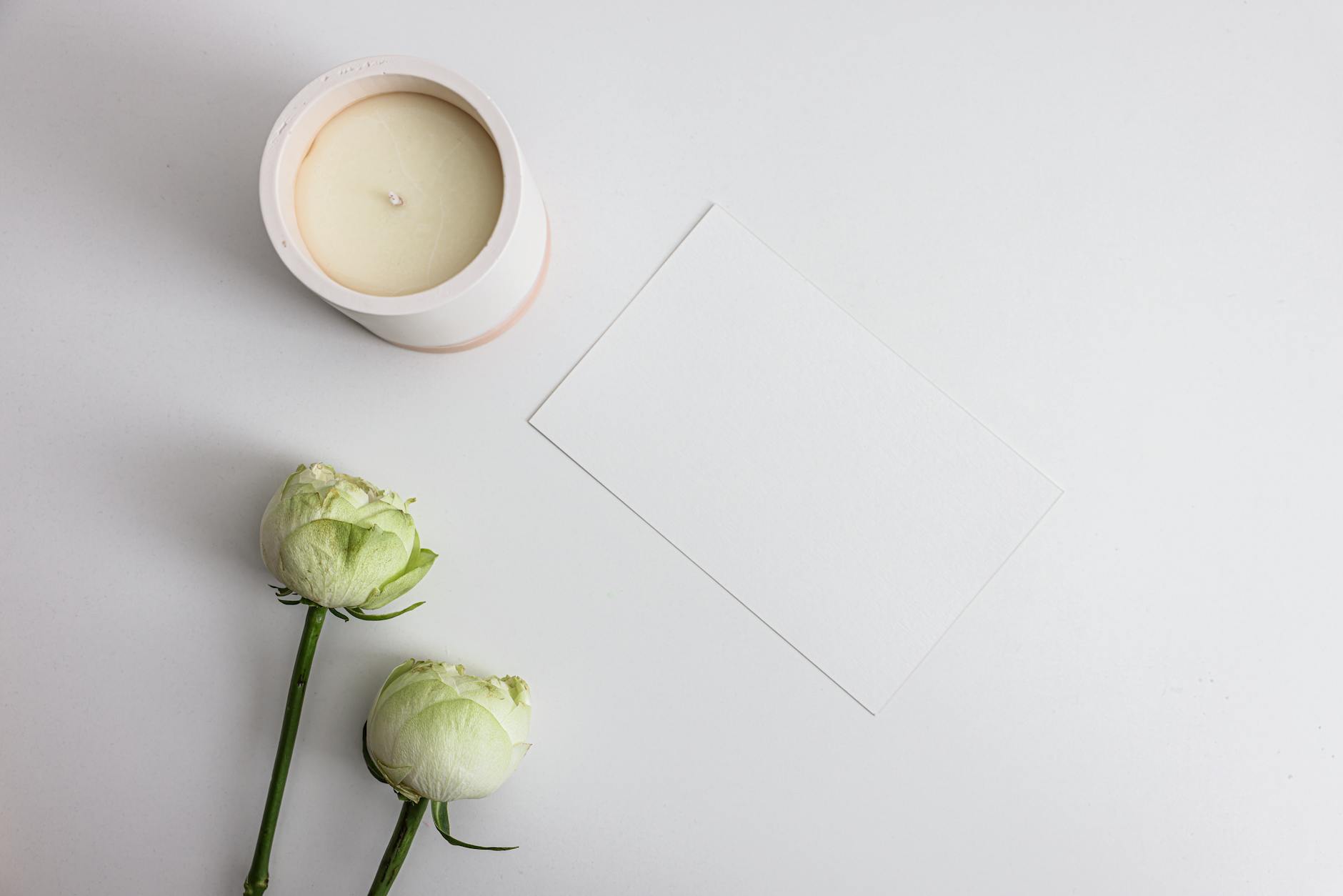Beautiful Flowers Near Scented Candle and Envelope on a White Surface