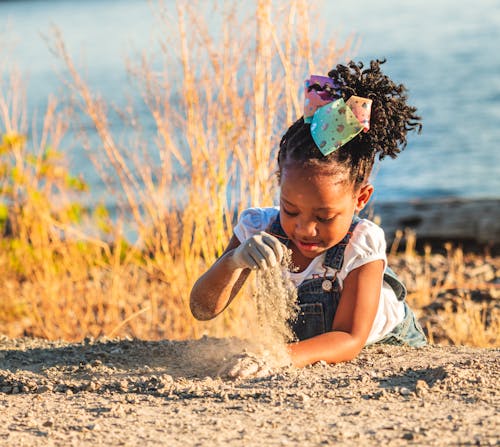 A Young Girl Lying Down while Playing a Sand