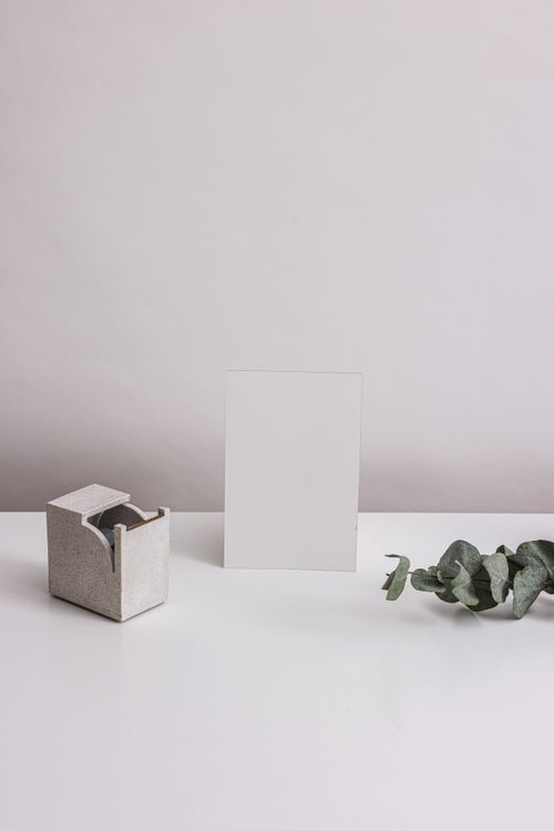 Free A minimalist composition featuring a blank card, eucalyptus branch, and concrete holder on a white surface. Stock Photo